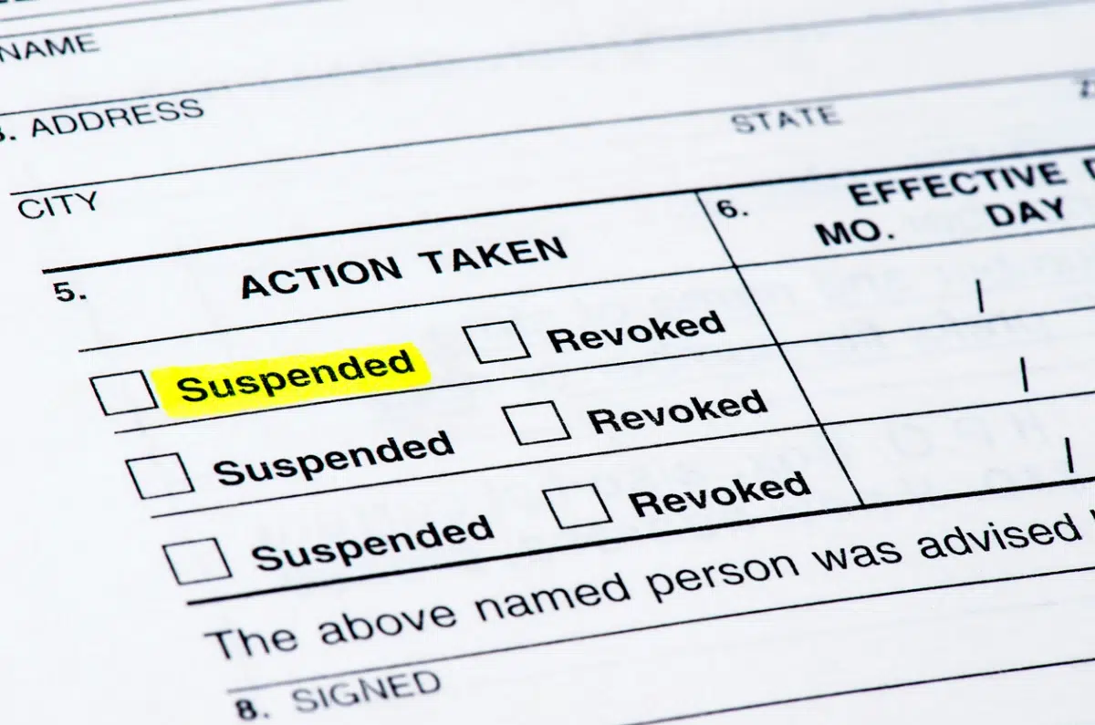 Official form showing "Action Taken" section with checkboxes for "Suspended" and "Revoked," with "Suspended" highlighted.
